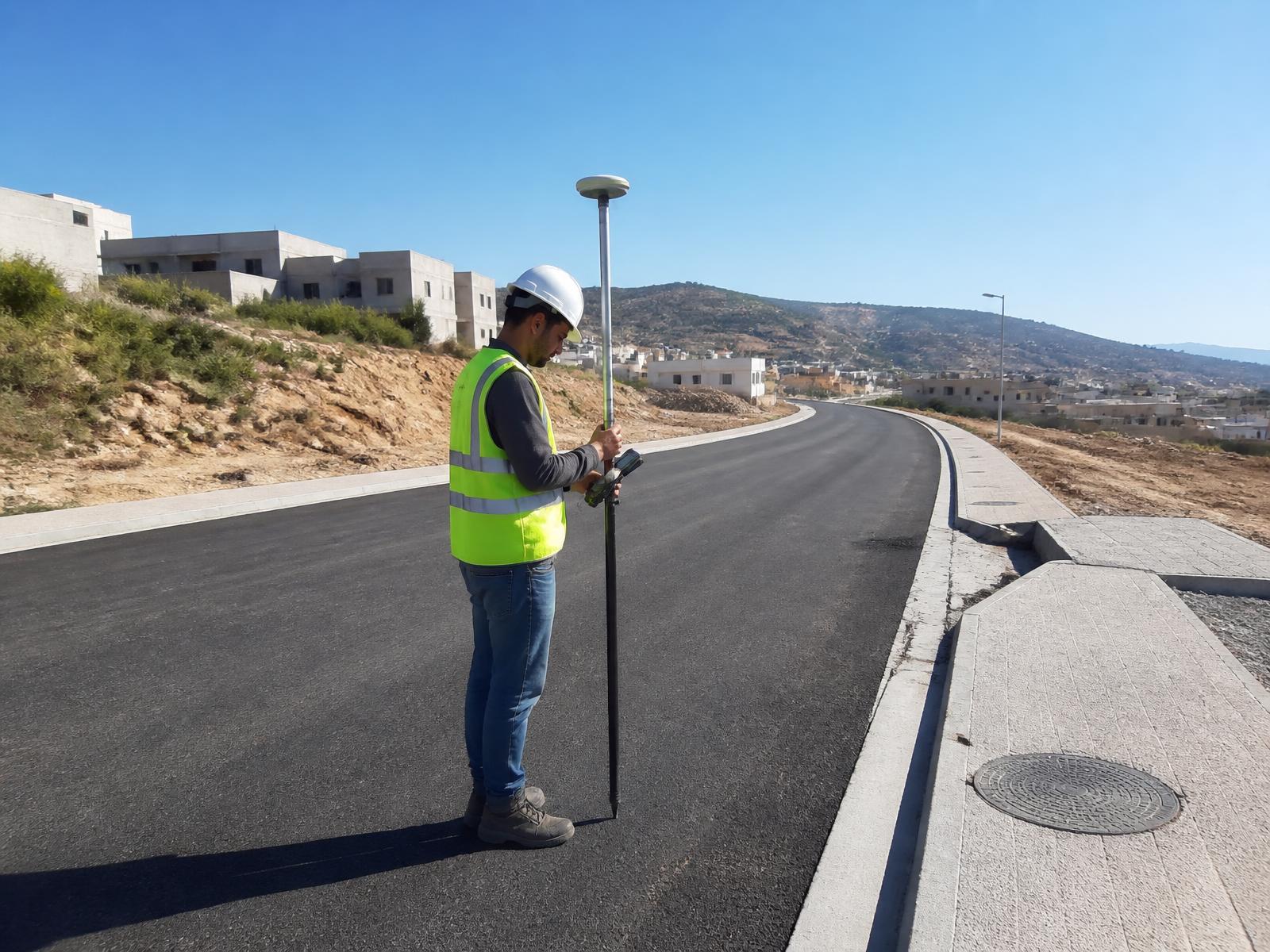 Surveyor recording as-built positions along a completed road using a GNSS RTK rover